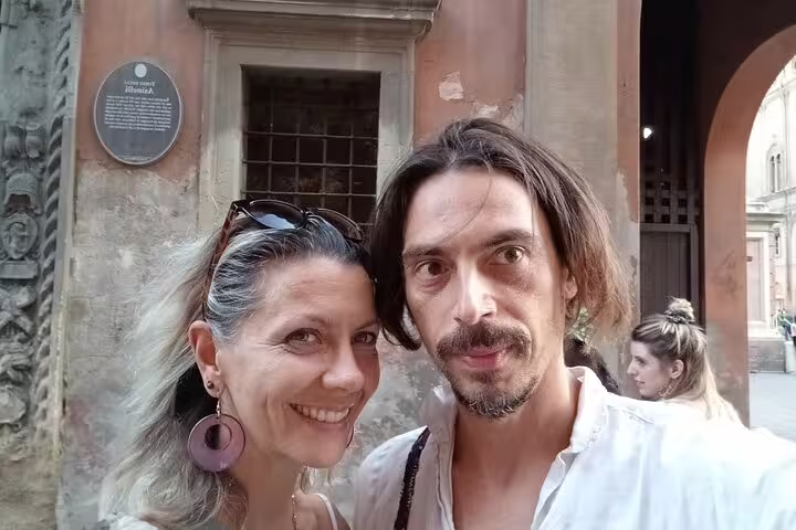 Couple taking selfie in front of historic Bologna building during walking tour of old town