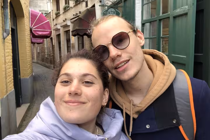 Two young tourists taking a selfie on a charming narrow street in Bruges