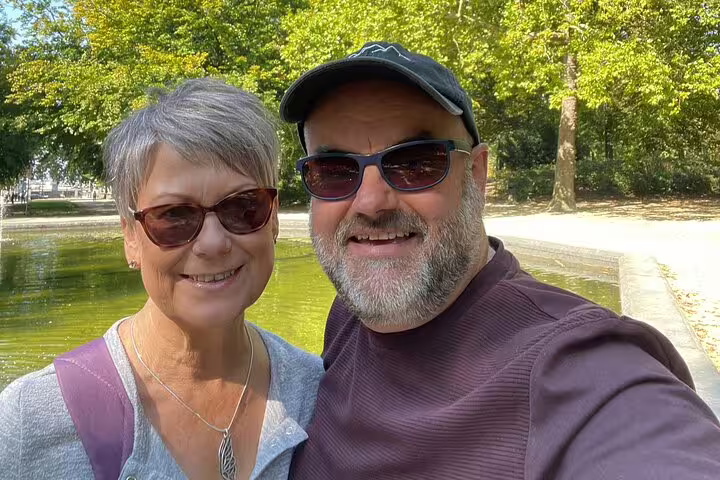 Smiling couple taking selfie in Brussels park near pond during beer walking tour