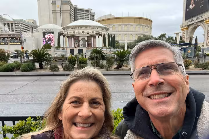 Smiling couple taking selfie in front of Caesars Palace on the Las Vegas Strip