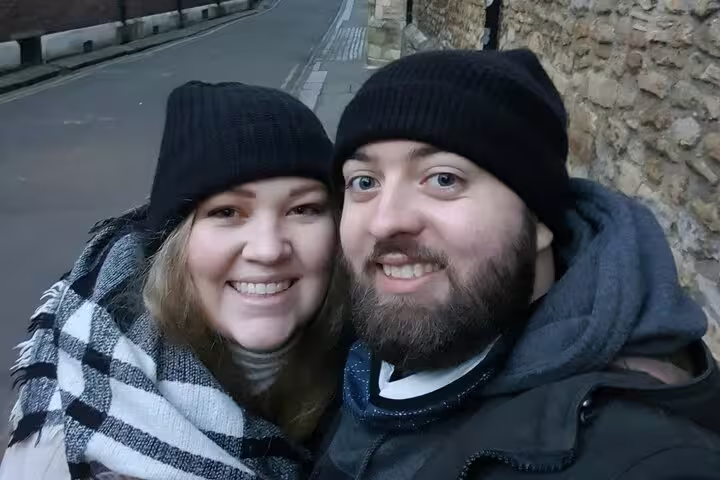Smiling couple in black beanies taking a selfie on a Cambridge street in winter