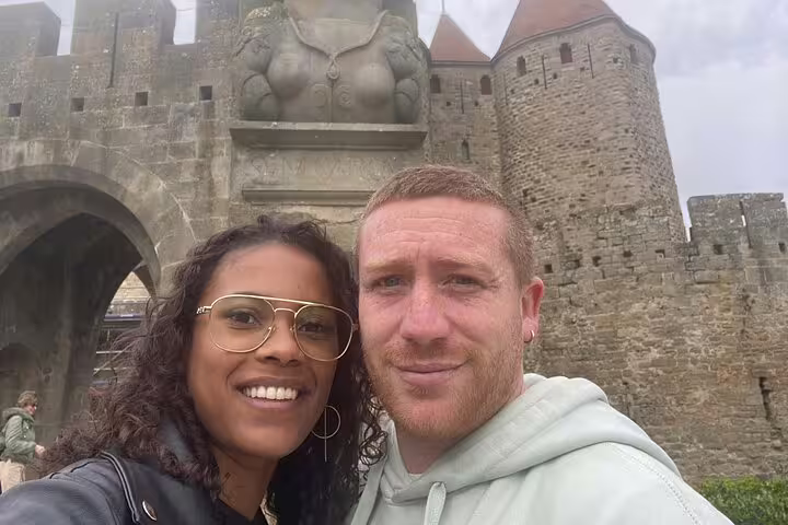 Couple taking selfie in front of Carcassonne medieval city castle gate and towers