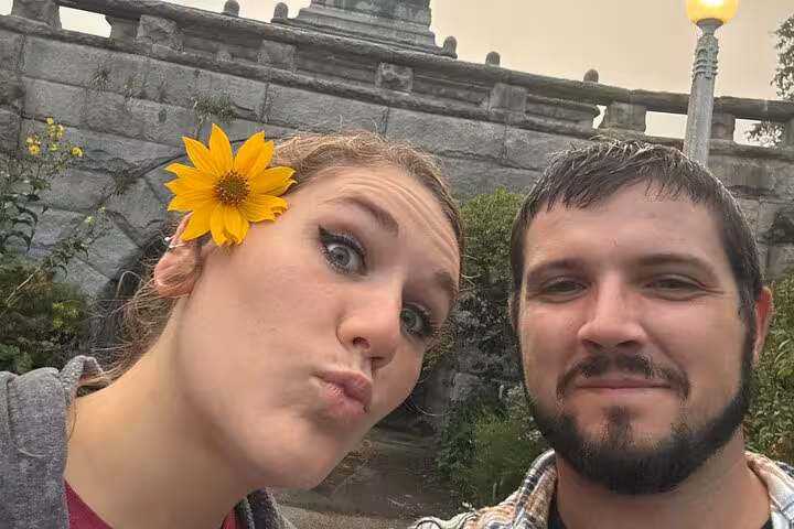 Couple posing for selfie near stone bridge and lamp post during Chicago ghost walking tour