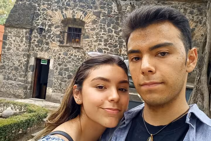 Young couple taking a selfie in front of a historic stone building in Chimalistac, Mexico City