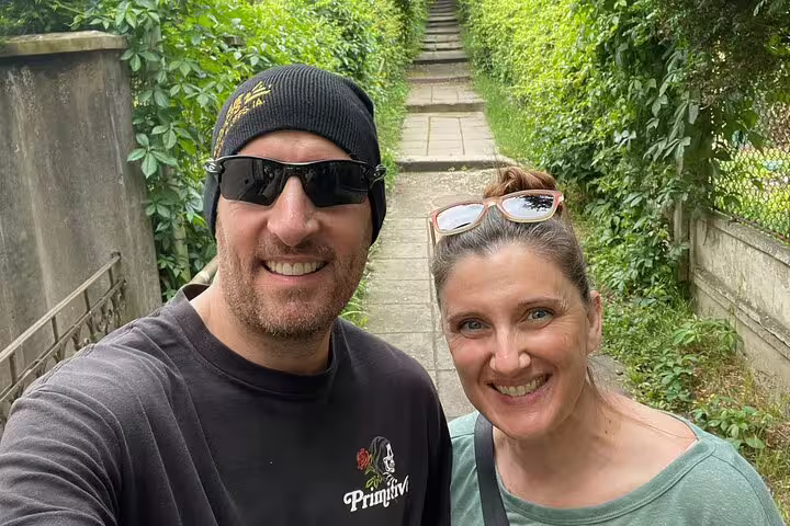 Couple smiling on a lush green narrow pathway during a walking tour in Cluj-Napoca
