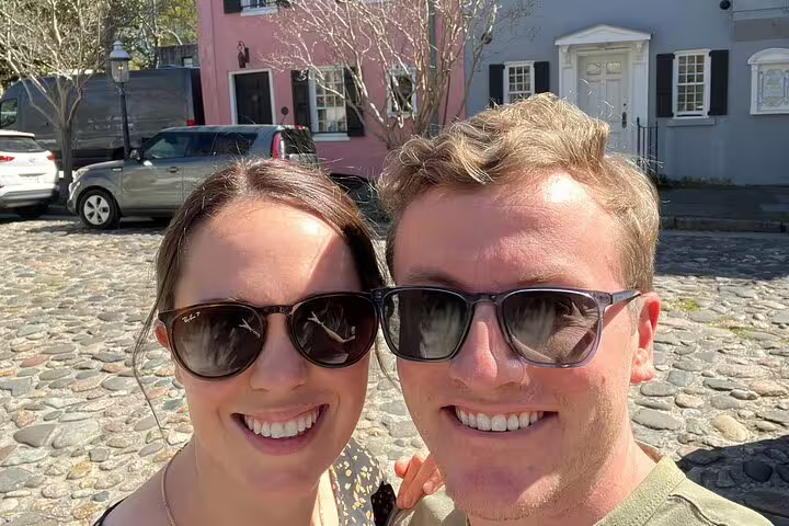 Smiling couple taking a selfie on a cobblestone street in historic Charleston, SC
