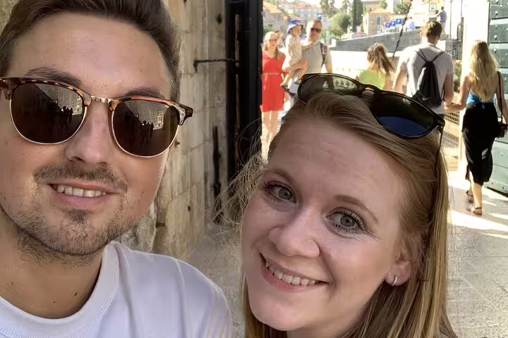 Smiling couple taking selfie on Dubrovnik Game of Thrones tour with historic stone walls