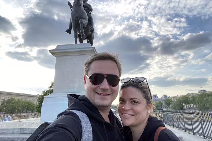 Couple taking selfie in front of equestrian statue along the Seine River in Paris