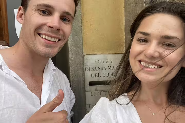 Smiling couple taking selfie outside Opera di Santa Maria del Fiore in Florence, Italy
