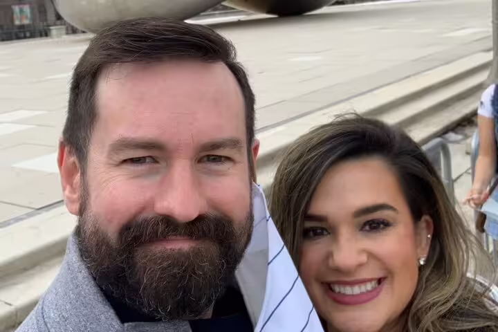 Couple smiling for selfie outdoors at Grant Park Chicago with urban landmark in background