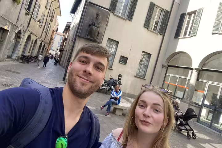 Couple taking a selfie on a historic cobblestone street in Como, Italy