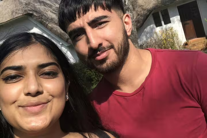 Couple taking a selfie outdoors near a historic building on a sunny day