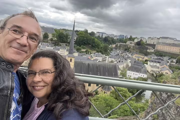 Couple taking selfie on scenic overlook above Luxembourg City's historic Grund neighborhood with church spire