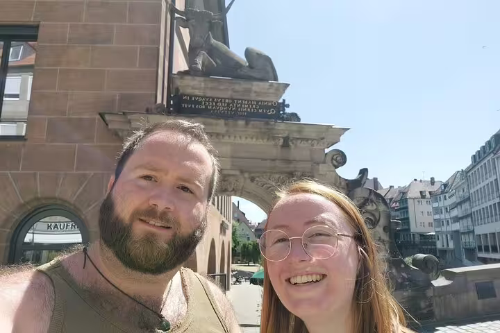 Couple smiling in front of medieval fountain sculpture in Nuremberg old town square