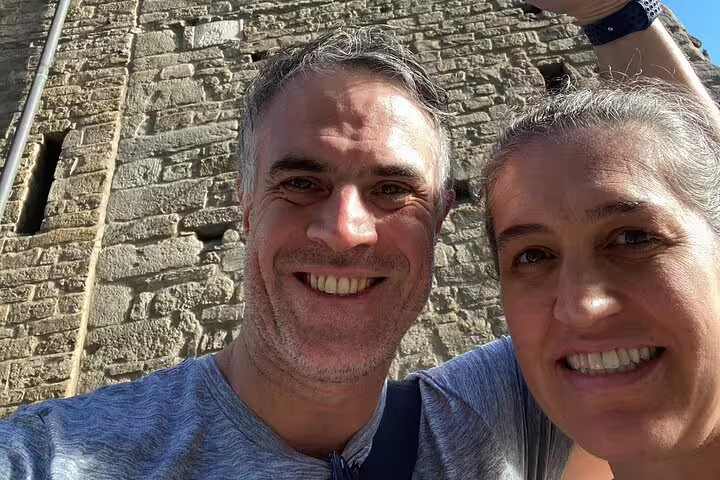 Couple smiling in selfie in front of ancient stone medieval building wall