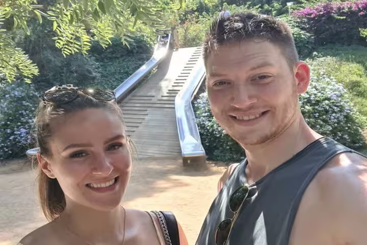 Couple smiling at Montjuic park with slides and lush greenery in Barcelona