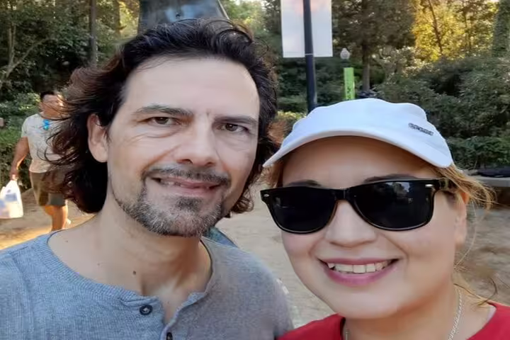 Smiling couple taking a selfie outdoors in a park setting on a sunny day