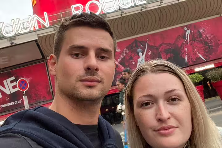 Couple taking selfie in front of Moulin Rouge in Montmartre, Paris
