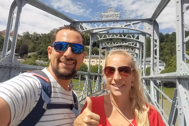 Couple taking a selfie on the historic Mozartsteg bridge in Salzburg Old Town on a sunny day