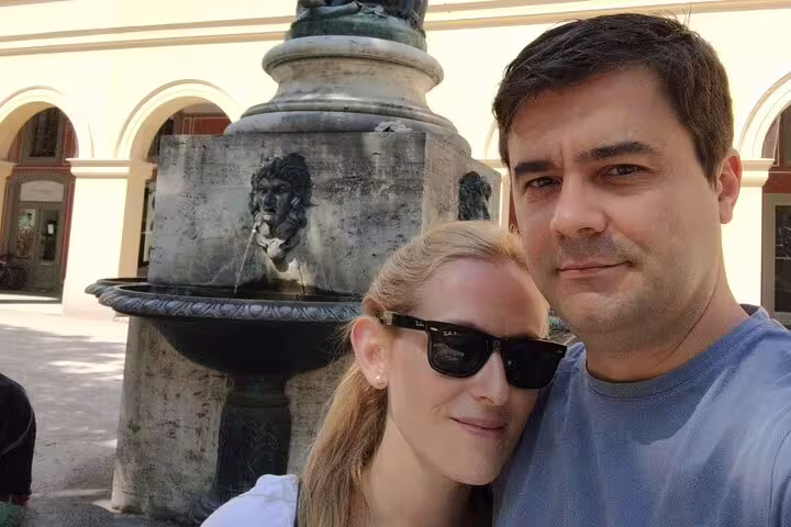 Couple taking selfie at ornate stone fountain in Munich Old Town square