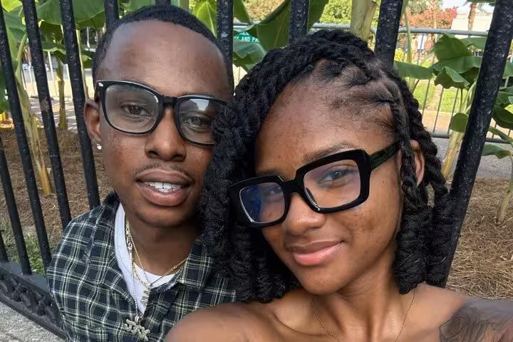 Couple taking a selfie near iron fence and tropical plants in New Orleans French Quarter