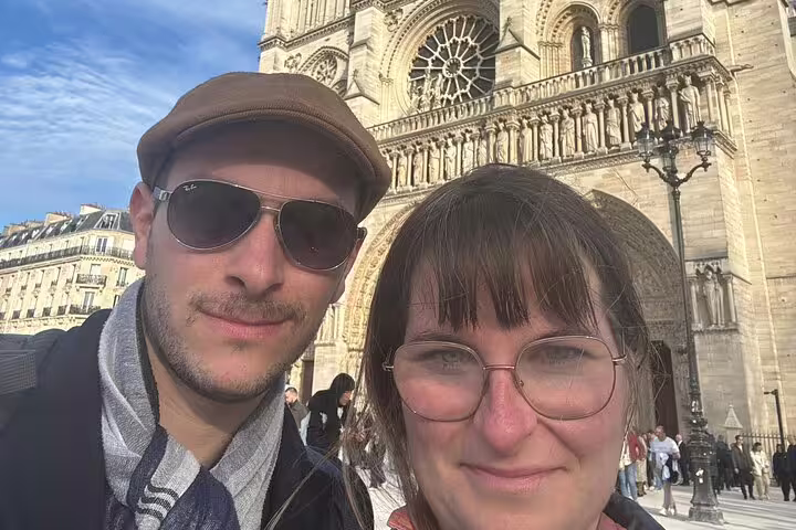 Couple taking a selfie in front of Notre-Dame Cathedral in Paris on a sunny day