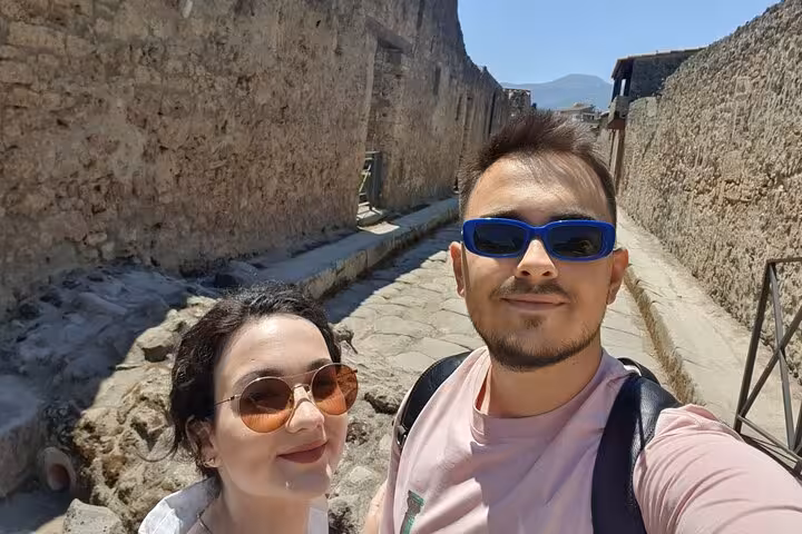 Couple taking selfie on ancient cobblestone street in Pompeii ruins on a sunny day