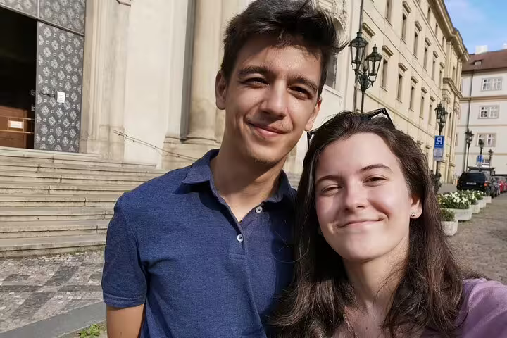 Young couple smiling together on a sunny cobblestone street in Prague Old Town
