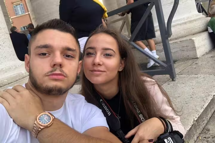 Couple taking a selfie at a Rome landmark during a walking tour, woman wearing Canon camera strap