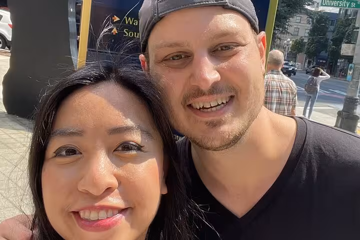 Smiling couple taking a selfie on a sunny Seattle street during a self-guided walking tour
