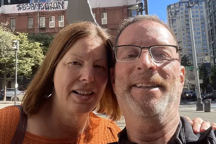 Smiling couple taking a selfie on a sunny Seattle street during a self-guided walking tour