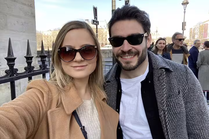 Couple taking a selfie along the Seine River in Paris on a sunny day