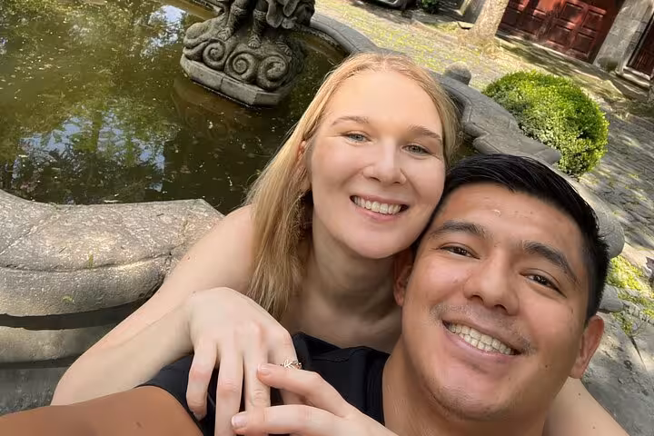 Smiling couple taking a selfie near a stone fountain in Chimalistac, Mexico City