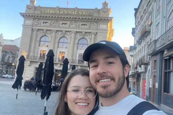 Couple smiling in selfie in front of Teatro Nacional São João in Porto Old Town