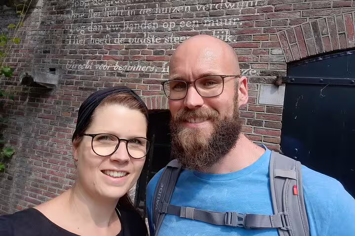 Couple smiling in front of historic brick wall with Dutch text in Utrecht city center