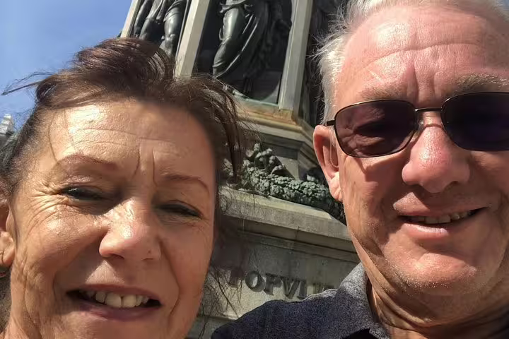 Couple smiling in selfie in front of historic bronze monument in Vienna