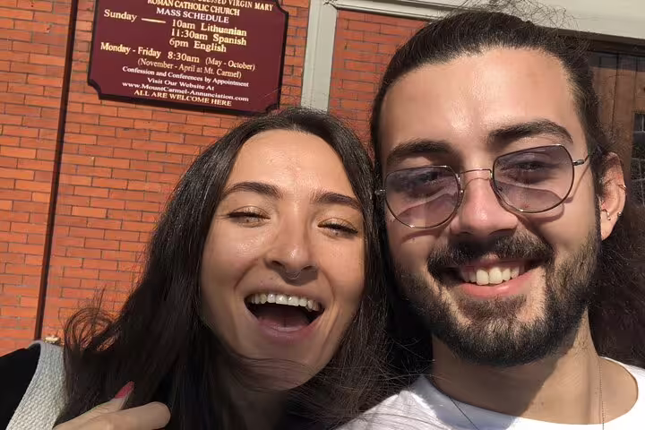 Two smiling friends taking a selfie in front of a Roman Catholic Church in Brooklyn Williamsburg