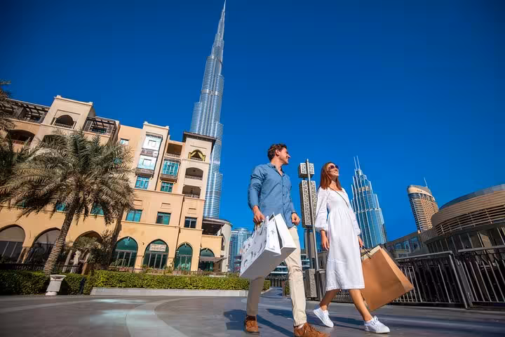 Couple walking with shopping bags near Burj Khalifa, perfect for capturing Instagram-worthy moments on a guided tour.