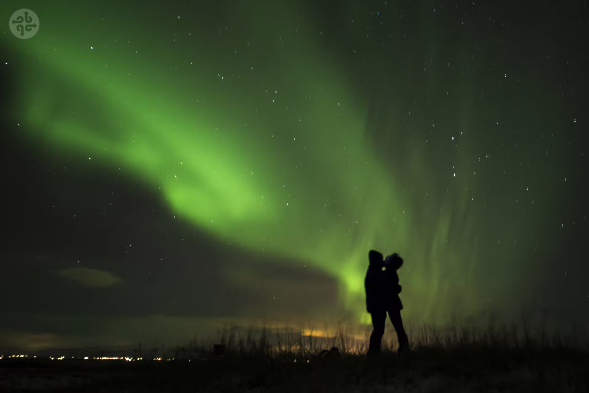 Couple silhouetted under vivid green northern lights aurora borealis in Iceland night sky