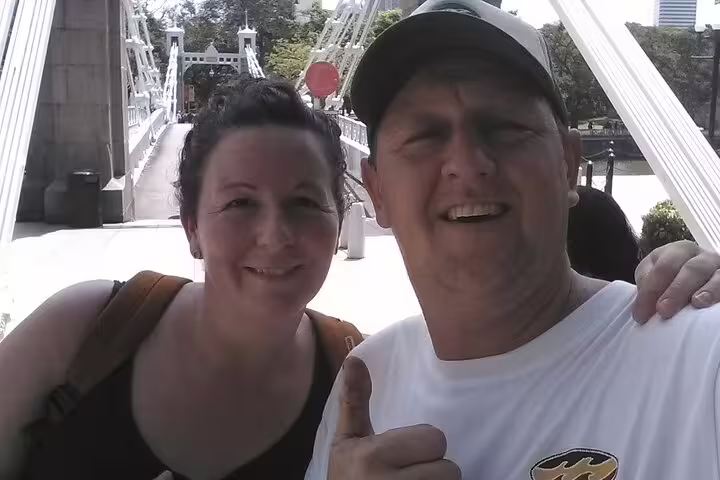 Couple smiling together on historic Cavenagh Bridge along Singapore's waterway