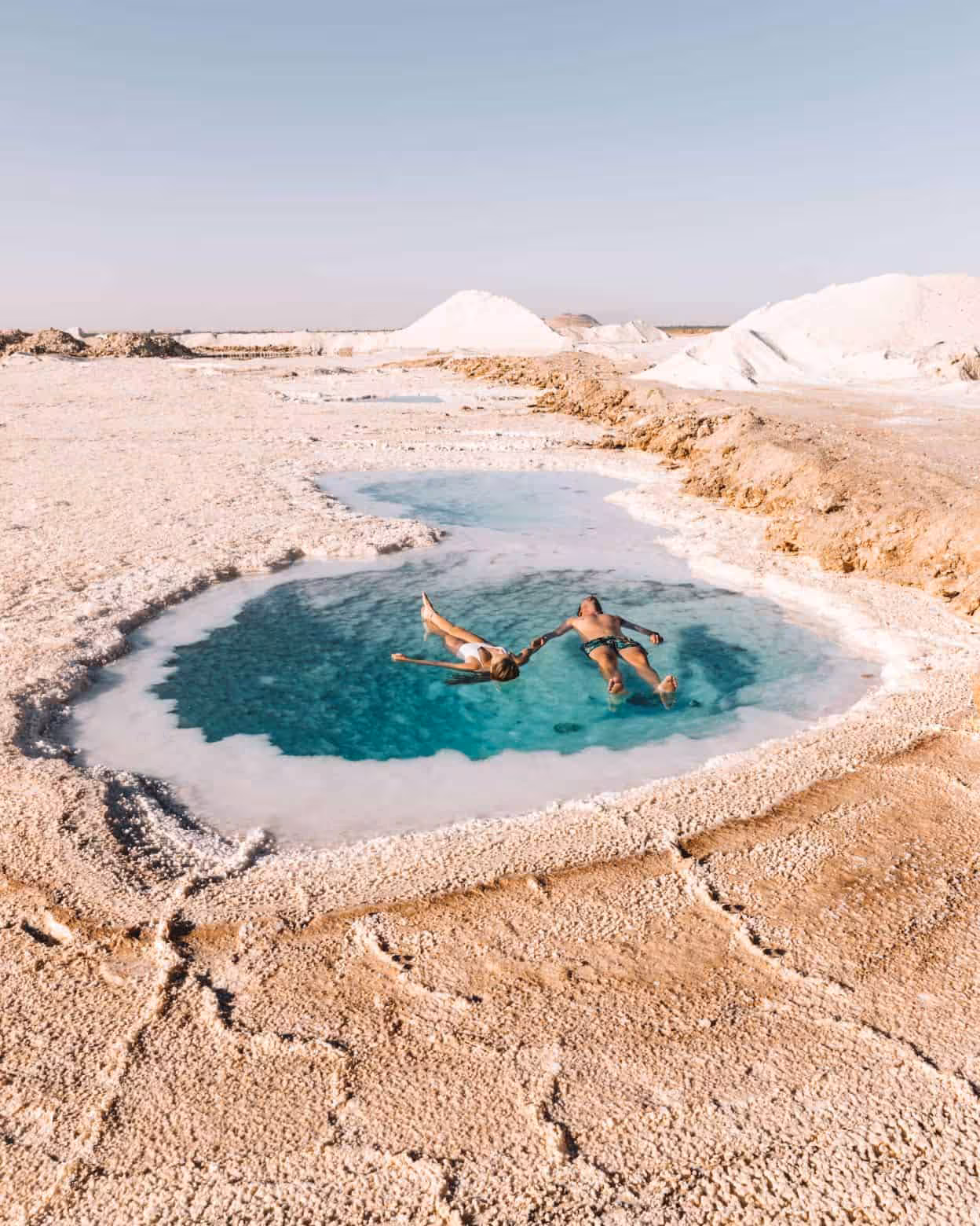 Couple floating in Siwa Oasis salt lake on a one-day tour from Marsa Matrouh, Egypt desert scenery