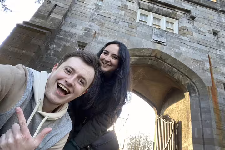 Smiling couple posing in front of a stone archway gate in Dublin