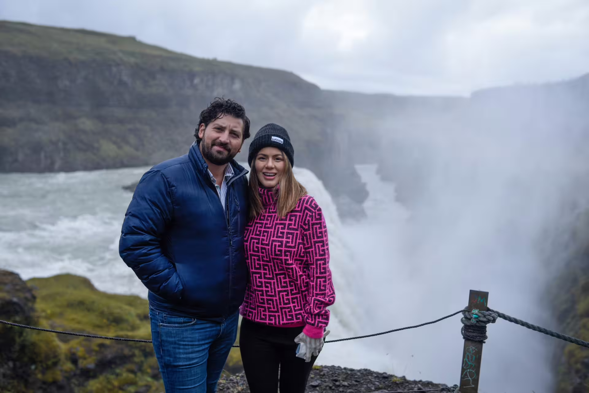 Happy couple smiling together at misty Gullfoss waterfall during a private Golden Circle day tour in Iceland