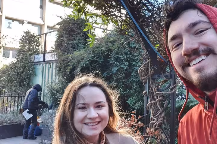 Smiling couple on a self-guided walking tour near London Bridge with green hedges in background