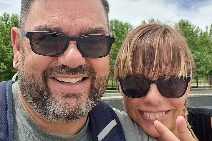 Smiling couple wearing sunglasses on a sunny outdoor walking tour in Madrid