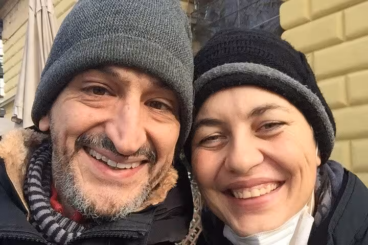 Smiling couple wearing winter hats enjoying Milan Navigli walking tour outdoor escape game