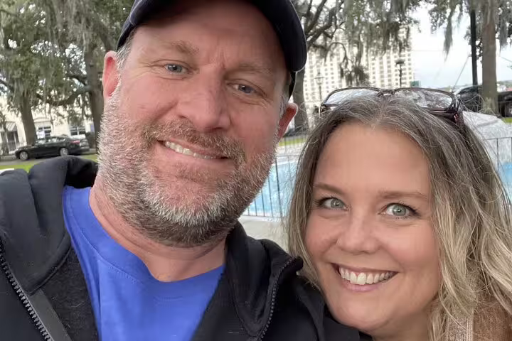 Smiling couple posing for selfie outdoors near Savannah waterfront with Spanish moss trees in background