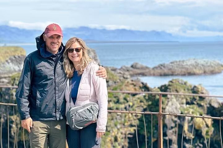 Couple smiling at scenic rocky coastline viewpoint on Snaefellsnes Peninsula tour