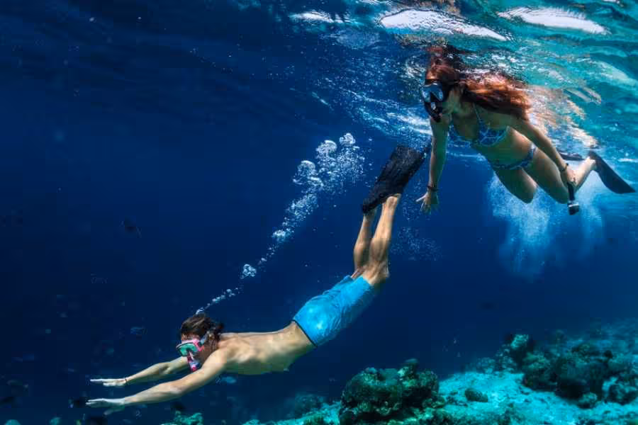 Couple snorkeling over coral reef in crystal-clear Red Sea on Marsa Mubarak snorkeling trip from Marsa Alam