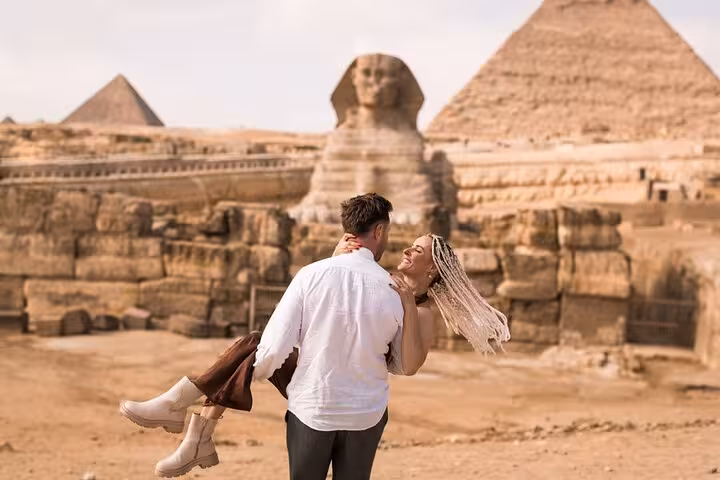Couple posing by the Sphinx with Giza Pyramids behind on Hurghada to Cairo pyramids and museum day trip